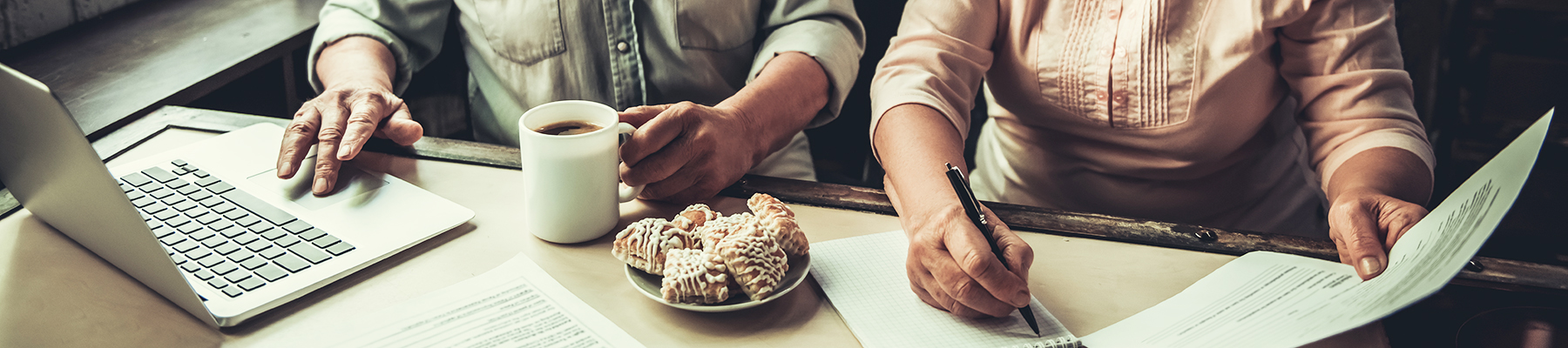 A couple sitting in their kitchen having breakfast and working on a laptop