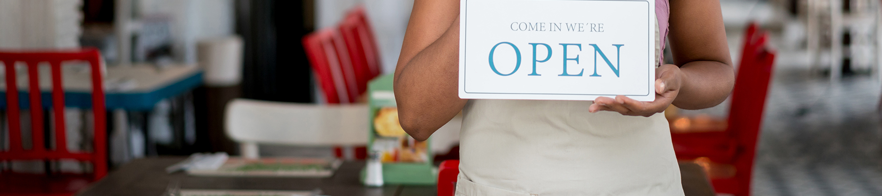 Woman in a cafe holding an open sign