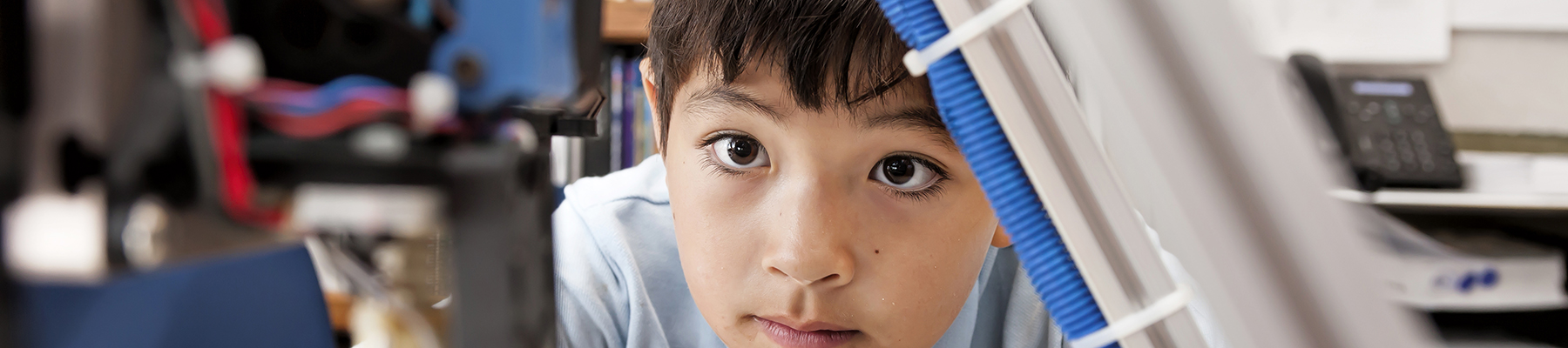 A young boy watching a 3D printing machine in progress